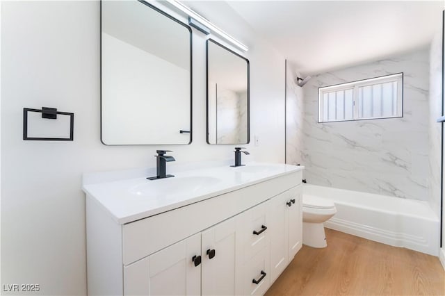 bathroom with double vanity, a sink, toilet, and wood finished floors