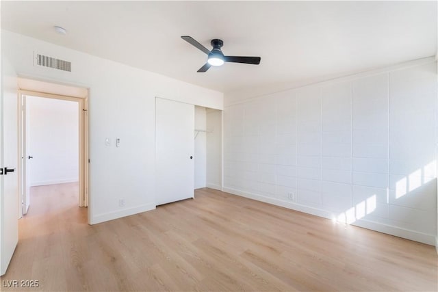 unfurnished bedroom with a closet, visible vents, light wood-style floors, ceiling fan, and baseboards