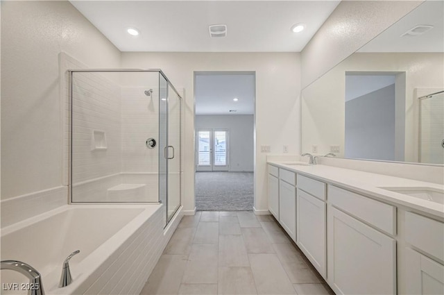 full bath featuring double vanity, a stall shower, and a sink