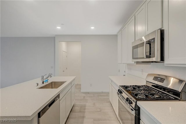 kitchen with recessed lighting, a sink, white cabinetry, baseboards, and appliances with stainless steel finishes