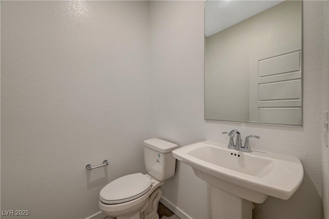 bathroom featuring a sink, toilet, and baseboards