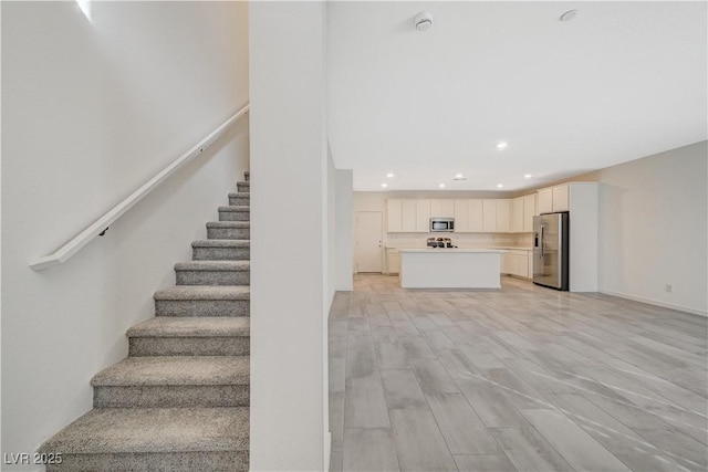 stairway featuring wood finished floors and recessed lighting