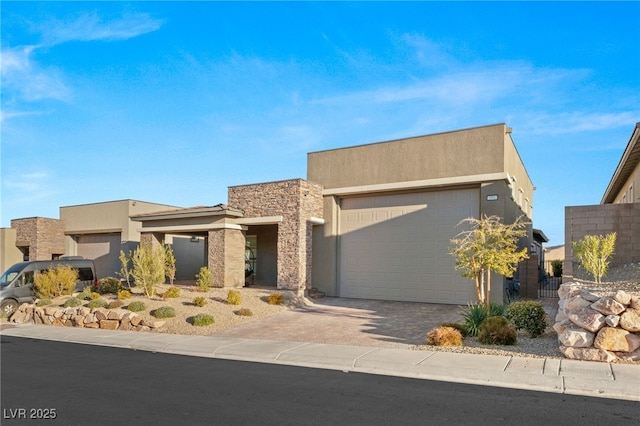 view of front of property featuring a garage, stone siding, decorative driveway, and stucco siding