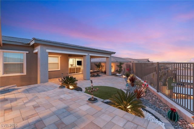 patio terrace at dusk featuring fence