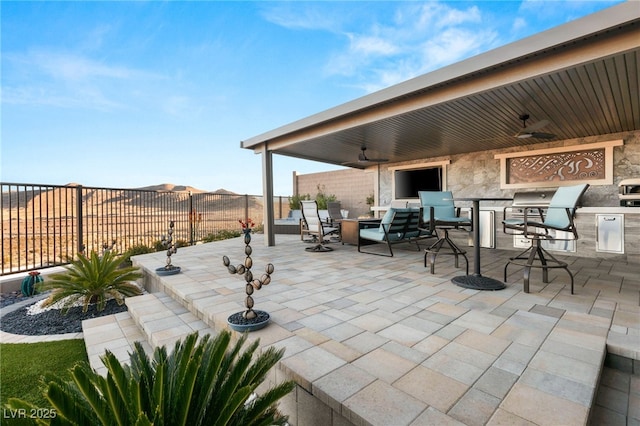 view of patio / terrace featuring fence, a ceiling fan, and exterior kitchen