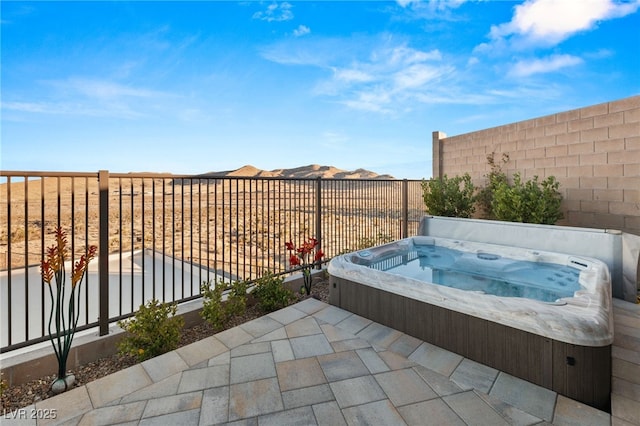 view of patio featuring a fenced backyard, a mountain view, and a covered hot tub