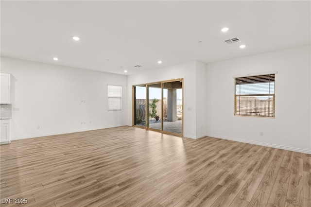 empty room featuring light wood-style floors, recessed lighting, a healthy amount of sunlight, and visible vents