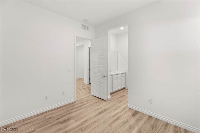 spare room with baseboards, visible vents, and light wood-style floors