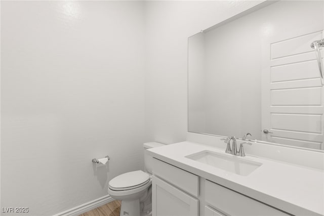 bathroom featuring wood finished floors, vanity, toilet, and baseboards