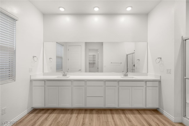 full bath featuring double vanity, a sink, and wood finished floors