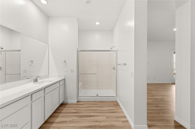 full bath with baseboards, a shower stall, vanity, and wood finished floors