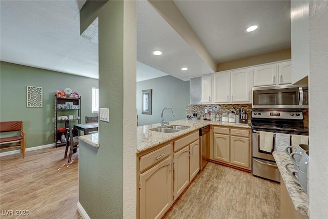 kitchen with stainless steel appliances, backsplash, light wood-type flooring, and a sink