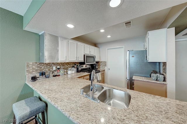 kitchen featuring tasteful backsplash, visible vents, stainless steel appliances, white cabinetry, and a sink