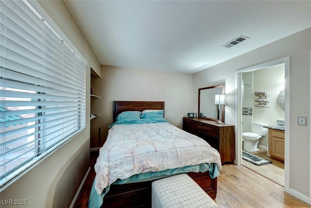 bedroom with baseboards, ensuite bathroom, visible vents, and light wood-style floors