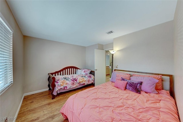 bedroom with visible vents, baseboards, and wood finished floors