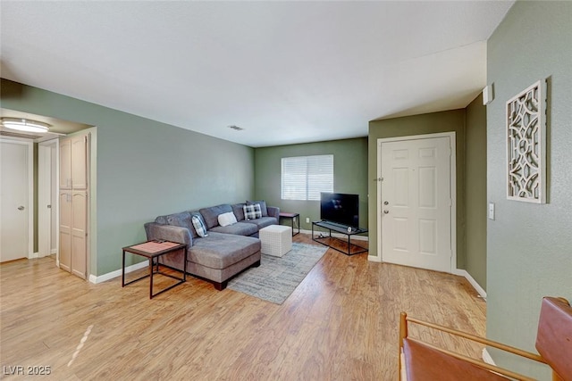 living area with light wood-type flooring, visible vents, and baseboards