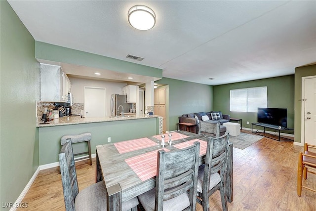 dining space featuring visible vents, light wood-style flooring, and baseboards