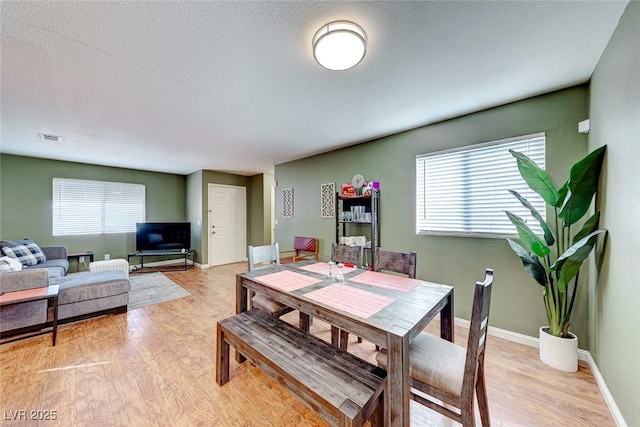 dining space featuring light wood-style floors, a wealth of natural light, and baseboards