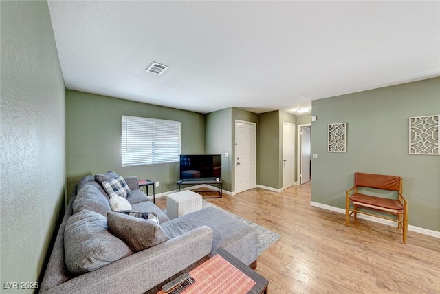 living area featuring light wood-type flooring, visible vents, and baseboards