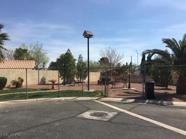 view of street featuring a gate, curbs, sidewalks, and street lights