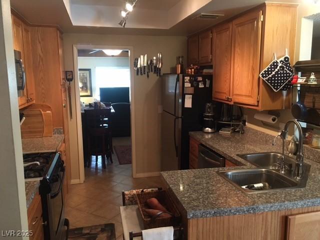 kitchen with a sink, range with gas cooktop, freestanding refrigerator, dishwasher, and a raised ceiling