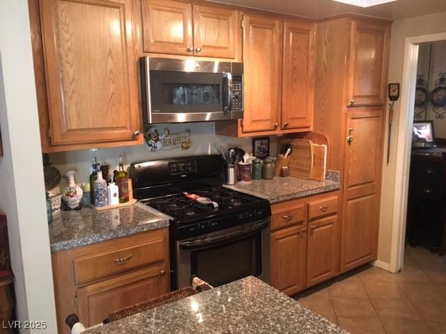 kitchen with light tile patterned floors, dark stone counters, and stainless steel appliances