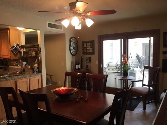 dining space with a textured ceiling, light tile patterned flooring, visible vents, and a ceiling fan