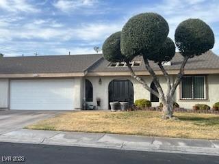 ranch-style home with concrete driveway, a front lawn, and an attached garage