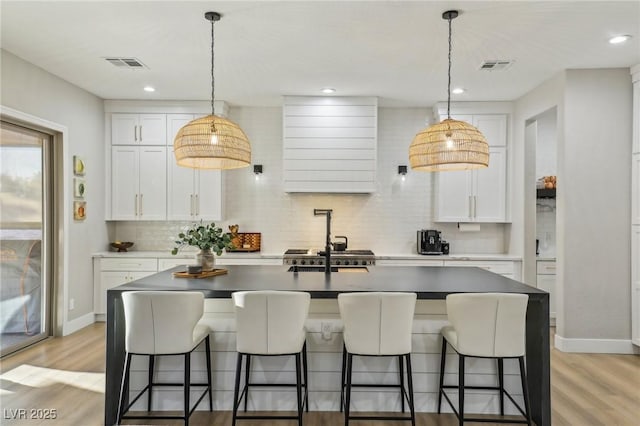 kitchen with light wood-style flooring, visible vents, and decorative backsplash