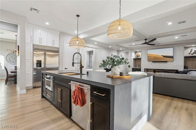 kitchen with visible vents, dark countertops, appliances with stainless steel finishes, light wood-style floors, and a sink