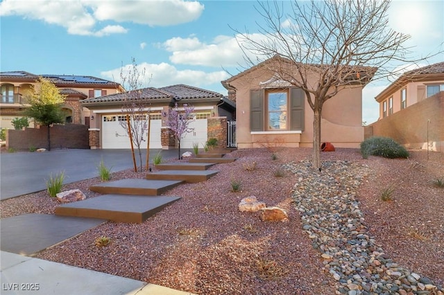 view of front of house featuring driveway, a garage, a tiled roof, fence, and stucco siding