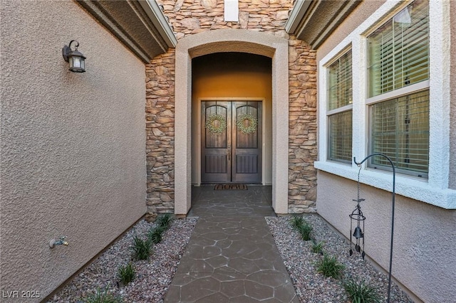 entrance to property featuring stone siding and stucco siding