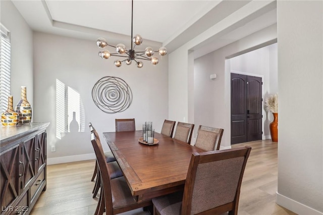 dining space featuring light wood-style floors, baseboards, and an inviting chandelier