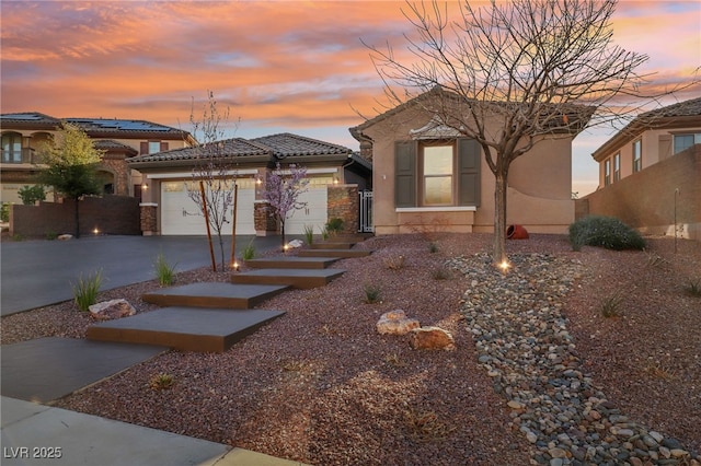 view of front of home featuring driveway, an attached garage, a tiled roof, and stucco siding