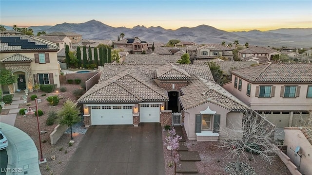 view of front of house featuring a garage, a tile roof, driveway, and a mountain view