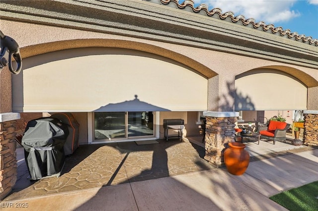 view of exterior entry featuring a patio and stucco siding