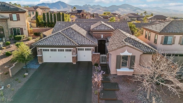 view of front of house with a garage, a tile roof, a residential view, aphalt driveway, and a mountain view