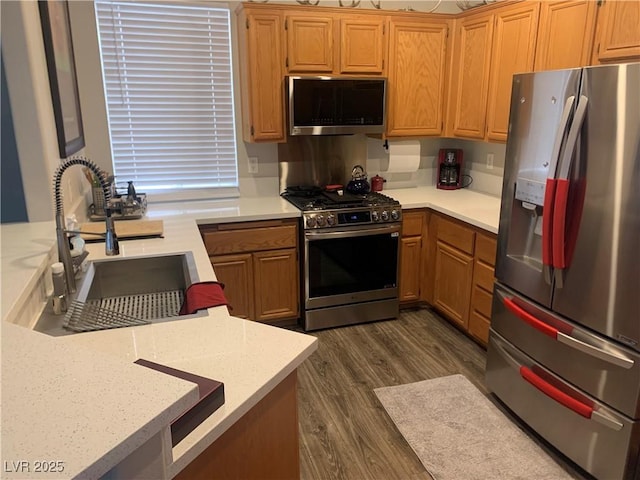 kitchen featuring dark wood finished floors, light countertops, appliances with stainless steel finishes, and a sink