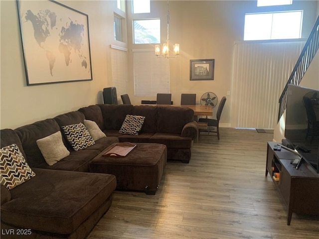 living area featuring stairs, a high ceiling, a notable chandelier, and wood finished floors