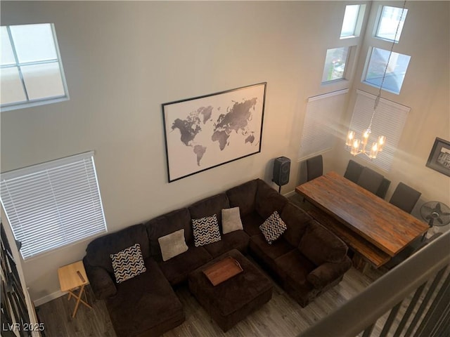 living area featuring a notable chandelier, a healthy amount of sunlight, baseboards, and wood finished floors