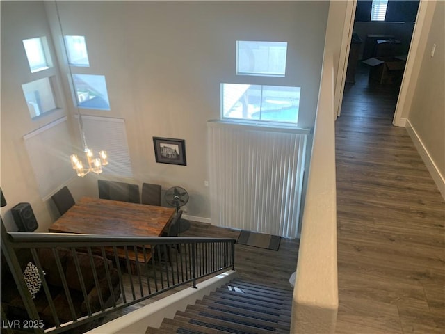 staircase featuring baseboards, an inviting chandelier, and wood finished floors