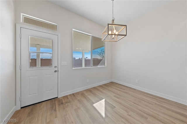 interior space featuring light wood finished floors, baseboards, and a chandelier