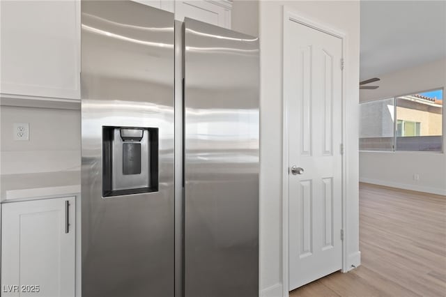 kitchen featuring white cabinets, light countertops, light wood-style flooring, and stainless steel fridge with ice dispenser