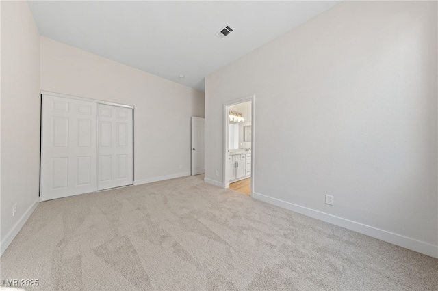 unfurnished bedroom with a closet, visible vents, light carpet, and baseboards