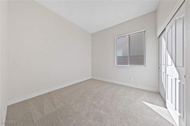 unfurnished bedroom featuring a closet, baseboards, vaulted ceiling, and carpet flooring