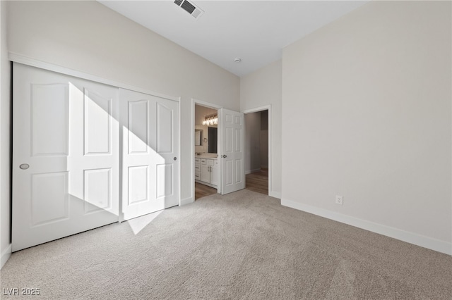 unfurnished bedroom featuring ensuite bathroom, visible vents, baseboards, a closet, and carpet