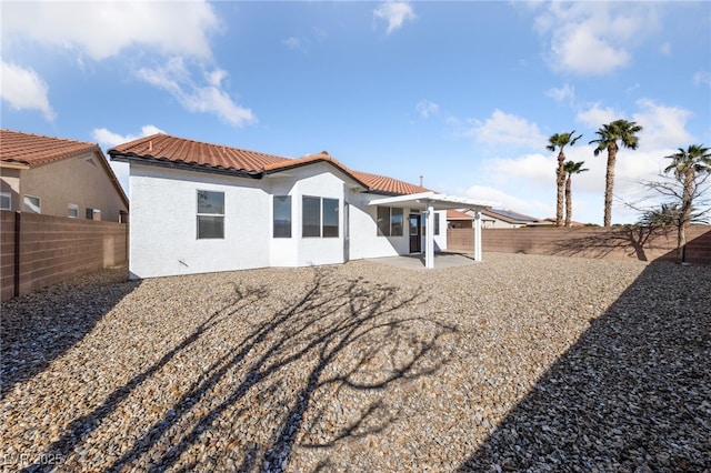 rear view of house featuring a tile roof, a fenced backyard, a patio, and stucco siding