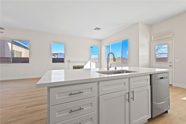 kitchen with a sink, a wealth of natural light, light countertops, and dishwasher