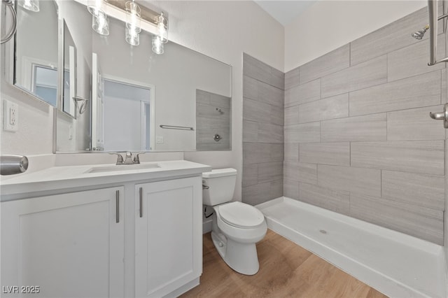 bathroom featuring tiled shower, vanity, toilet, and wood finished floors