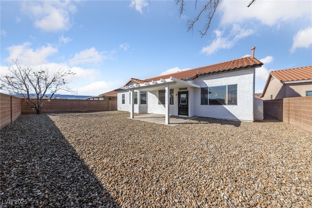 rear view of property featuring a patio area, a fenced backyard, stucco siding, and a tiled roof